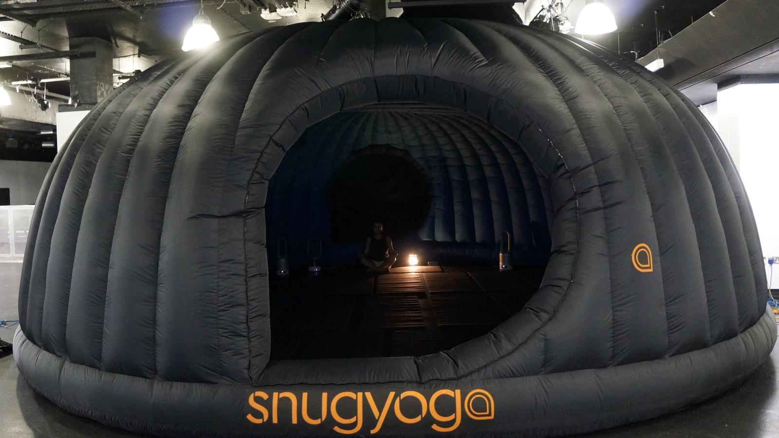 Inside the Snug Yoga heated dome pod — person meditating in warm amber light